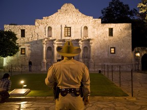 Rear view of a Texas Ranger standing in front of the Alamo at twilight, San Antonio, Texas.