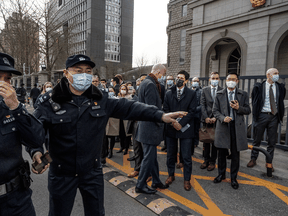 Police keep reporters back from the road as U.S. Embassy Acting Deputy Chief of Mission William Klein, center, and other diplomats request entry to the trial for Canadian Michael Kovrig on March 22, 2021 at a court in Beijing, China.