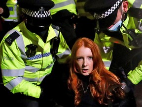 Police detain a woman as people gather at a memorial site in Clapham Common Bandstand, following the kidnap and murder of Sarah Everard, in London, Britain March 13, 2021.
