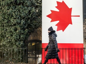 A pedestrian passes a Canadian flag in Toronto's Yorkville area on March 4, 2021. A reader makes a plea for Canadian unity in the Letters to the Editor.