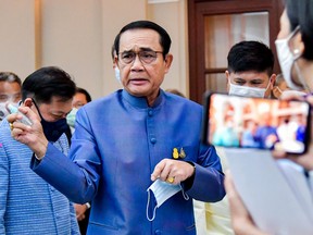 This handout from the Royal Thai Government taken and released on March 9, 2021 shows Thailand's Prime Minister Prayut Chan-O-Cha spraying hand sanitiser at journalists in an attempt to avoid questions about the cabinet reshuffle during a press conference in Bangkok.