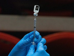 A health-care worker prepares a dose of the Pfizer-BioNTech COVID-19 vaccine on the campus of San Diego State University in San Diego, Calif., on April 1, 2021.