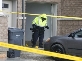 An SIU (Special Investigations Unit) official exits a garage on Adventura Rd. southeast of Mississauga and Mayfield Rd.where shell casings are under markers.