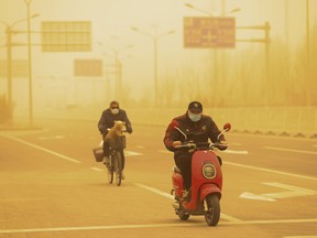 People wearing ride their bikes along a street during a sandstorm on March 15, 2021 in Beijing, China.