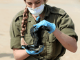 An Israeli soldier holds a clump of tar cleaned from the sand after an offshore oil spill deposited tar along Israel's Mediterranean shoreline, at a beach in Atlit, Israel, February 22, 2021.