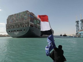 A picture released by Egypt's Suez Canal Authority on March 29, 2021, shows a man waving the Egyptian flag after Panama-flagged MV 'Ever Given' container ship was fully dislodged from the banks of the Suez.
