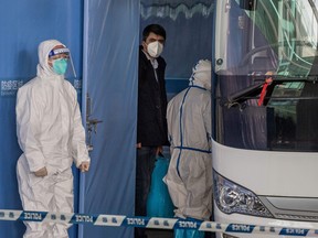 Vladimir G. Dedkov, centre, a member of the World Health Organization (WHO) team investigating the origins of the COVID-19 pandemic, boards a bus following the team's arrival at a cordoned-off section in the international arrivals area at the airport in Wuhan on Jan. 14, 2021.