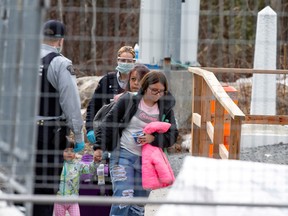 Asylum seekers cross the border from New York into Canada followed by Royal Canadian Mounted Police in Quebec on March 2020