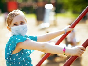 modern child with medical mask on playground outdoors in city