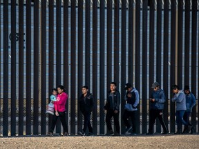 Undocumented immigrants walk along the U.S.-Mexico border wall after they ran across the shallow Rio Grande into El Paso on March 17, 2021 in Ciudad Juarez, Mexico.
