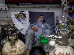 Patients suffering from COVID-19 share a bed as they receive treatment at the casualty ward in New Delhi, on April 15