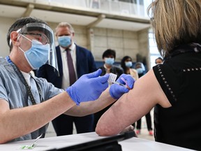 Ontario Premier Doug Ford, back centre, watches as a doctor administers the coronavirus vaccine to a nurse at a mass COVID-19 vaccination clinic in Mississauga, Ont., on March 1.