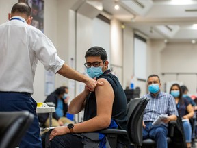 Ruben Rodriguez, the team lead from Humber River Hospital's mobile vaccine clinic, administers the first dose of the Moderna COVID-19 vaccine to an employee of pharmaceutical company Apotex in Toronto, April 13, 2021.