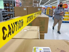 A person walks past cordoned off aisles of non-essential goods at a Walmart store in Toronto