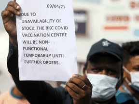 A guard holds up a notice to inform people about the shortage of COVID-19)vaccine supplies at a vaccination centre, in Mumbai, India.
