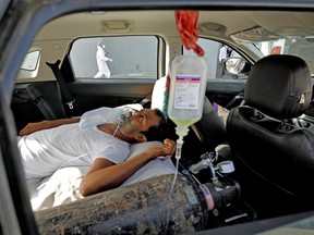 A patient with breathing problems waits inside a car to enter a COVID-19 hospital for treatment in Ahmedabad, India, April 22, 2021.
