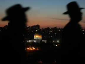 Ultra-Orthodox Jews walk past the Dome of the Rock in the background.