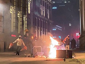 Vandals feed flames during an anti-curfew protest in Montreal on Sunday April 11, 2021.