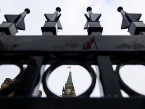 The Peace Tower is seen through an iron fence on Parliament Hill.