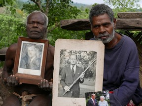 Village chief Jack Malia from Tanna Island, left, and a fellow villager hold photos of Prince Philip and Queen Elizabeth in Younanen, where the prince is worshipped, on May 6, 2017. Picture taken May 6, 2017. In the photo on the right, Philip is holding a Tannese club used to kill wild pigs that the tribe sent him.