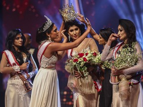 In this photograph taken on April 4, 2021, winner of Mrs. Sri Lanka 2019 Caroline Jurie (second left) removes the crown of 2020 winner Pushpika de Silva (centre).