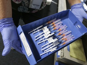 A pharmacist holds a container of fully loaded syringes of Pfizer-BioNTech COVID-19 vaccine to be administered to 1,500 people at a vaccination clinic held at Toronto's Downsview Arena on April 21, 2021.