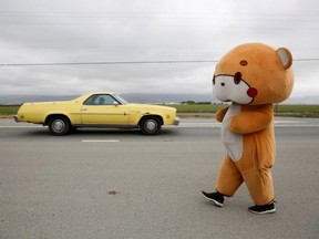 Jesse Larios, 33, from Los Angeles, wears a bear suit while walking along Hollister Road in Gilroy, California, U.S., April 21, 2021. Larios, also known as Bear Sun on social media, is walking from his home in Los Angeles to San Francisco while wearing the bear suit as a social media fundraising event.