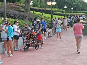 Guests wearing protective masks wait to pick up their tickets at the Magic Kingdom theme park at Walt Disney World on the first day of reopening, in Orlando, Florida, on July 11, 2020. A man was arrested for trespassing after he walked into the park without taking a temperature check.