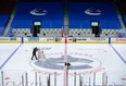 An arena worker removes the net from the ice after the Vancouver Canucks and Calgary Flames NHL hockey game was postponed due to a positive COVID-19 test result, in Vancouver, on Wednesday, March 31, 2021.