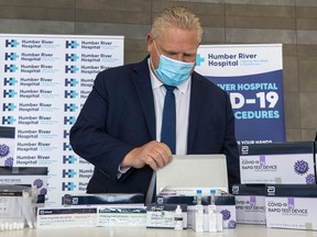 Ontario Premier Doug Ford examines COVID-19 Rapid Test Device kits at Humber River Hospital in Toronto on Nov. 24, 2020.