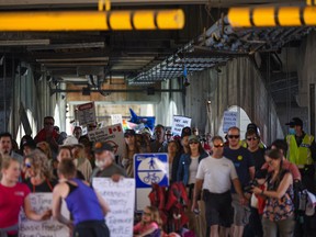 A crowd of over 200 people are seen crossing the lower deck of the Centre Street bridge in Calgary during a rally to protest the COVID-19 restrictions on Saturday, April 17, 2021.