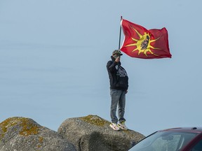 A warrior flag flies as members of the Sipekne'katik First Nation gather on the wharf in Saulnierville, N.S., to bless the fleet before it launches its own self-regulated fishery on Thursday, Sept. 17, 2020.