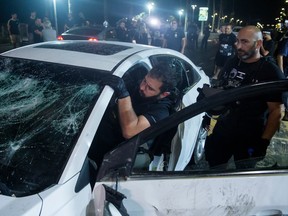 An Israeli police officer inspects the car of an Israeli Arab man who was attacked and injured by an Israeli Jews mob on May 12, 2021 in Bat Yam, Israel