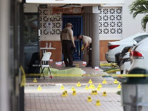 Miami-Dade police investigate near shell case evidence markers on the ground where a mass shooting took place outside of a banquet hall on May 30, 2021 in Hialeah, Florida.