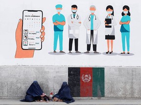 Afghan women clad in burkas beg under a wall mural in Kabul on April 19, 2021. According to a recent editorial in a Taliban publication, cries for women's rights are a "colonial tool."