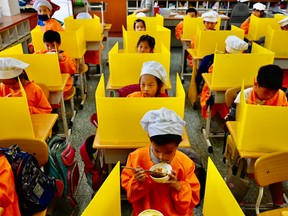 Students eat their lunch on desks with plastic partitions as a preventive measure to curb the spread of COVID-19 at Dajia Elementary School in Taipei on April 29, 2020.