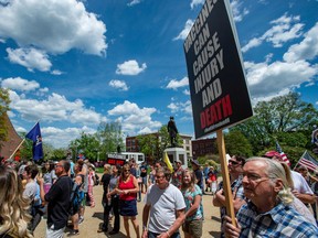 Rally goers hold signs protesting vaccines at an anti-vaccine rally in Concord, N.H., on May 15.