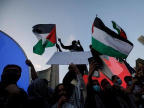 People wave flags and chant during a demonstration to voice support for the people of Palestine, at Toronto City Hall on May 15.