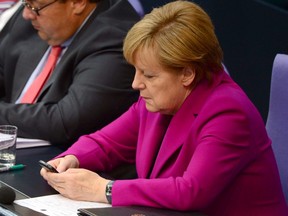 This file photo taken on June 4, 2014, shows German Chancellor Angela Merkel holding her mobile phone during a session of the Bundestag Lower House of parliament in Berlin.