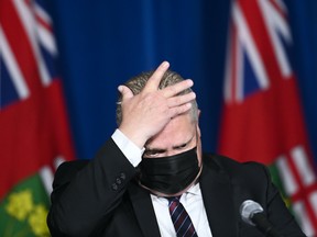 Ontario Premier Doug Ford wipes his head as he holds a press conference regarding the plan for Ontario to open up at Queen's Park during the COVID-19 pandemic in Toronto May 20, 2021.