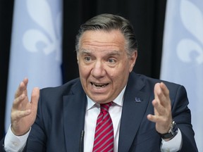 Quebec Premier Francois Legault, centre responds to reporters questions during a news conference on the COVID-19 pandemic, Tuesday, March 23, 2021 at the legislature in Quebec City.