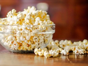 Closeup Popcorn in a glass cup on a wooden table and blurry background.