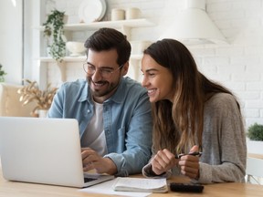 Happy young couple paying bills online in computer app