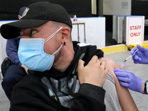 A man is inoculated by a health worker from Humber River Hospital during a vaccination clinic for residents 18 years of age and older who live in coronavirus disease (COVID-19) "hot spots" at Downsview Arena in Toronto, Ontario, Canada April 21, 2021.