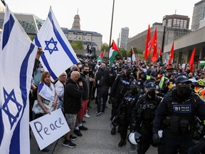 Police officers stand in line to separate protesters supporting Palestine from a small group of Israel supporters in front of city hall in Toronto, Ontario, Canada May 15, 2021.