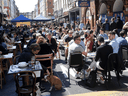 People packed on a London restaurant patio as COVID lockdown restrictions eased in Britain, April 24, 2021. In the space of three months, the U.K.’s daily average death toll dropped from 1,244 to 26; it is now at 13.