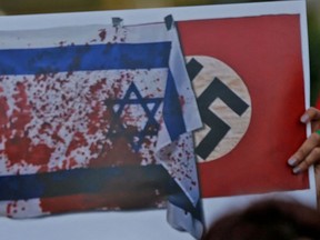 A bloodied Israeli flag and a sign bearing a swastika are seen at an anti-Israeli protest in Ramallah, in the West Bank, on May 20, 2021.