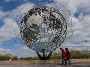 A couple walks past the Unisphere sculpture in Flushing Meadows Corona Park on Earth Day, April 22, 2021, in New York City. Canada needs to adopt a more pragmatic approach to climate change, writes Derek H. Burney.