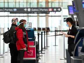 People wearing protective equipment check in at the international departures at Pearson International Airport during the COVID-19 pandemic in Toronto on Monday, December 14, 2020.