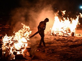 A worker helps cremate the bodies of Covid-19 victims on the banks of the Ganges river May 06, 2021 in Allahabad, Uttar Pradesh, India. India broke a fresh record on Thursday with over 412,000 new cases of Covid-19 as the total number of those infected according to Health Ministry data neared 20 million.